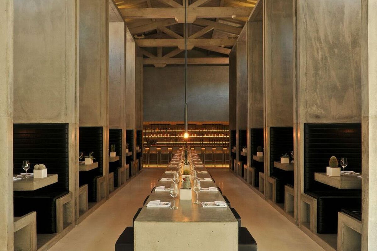 A large and long communal table stretches the length of the dining room with tall banquette tables surrounding from near to end at Workshop Kitchen.